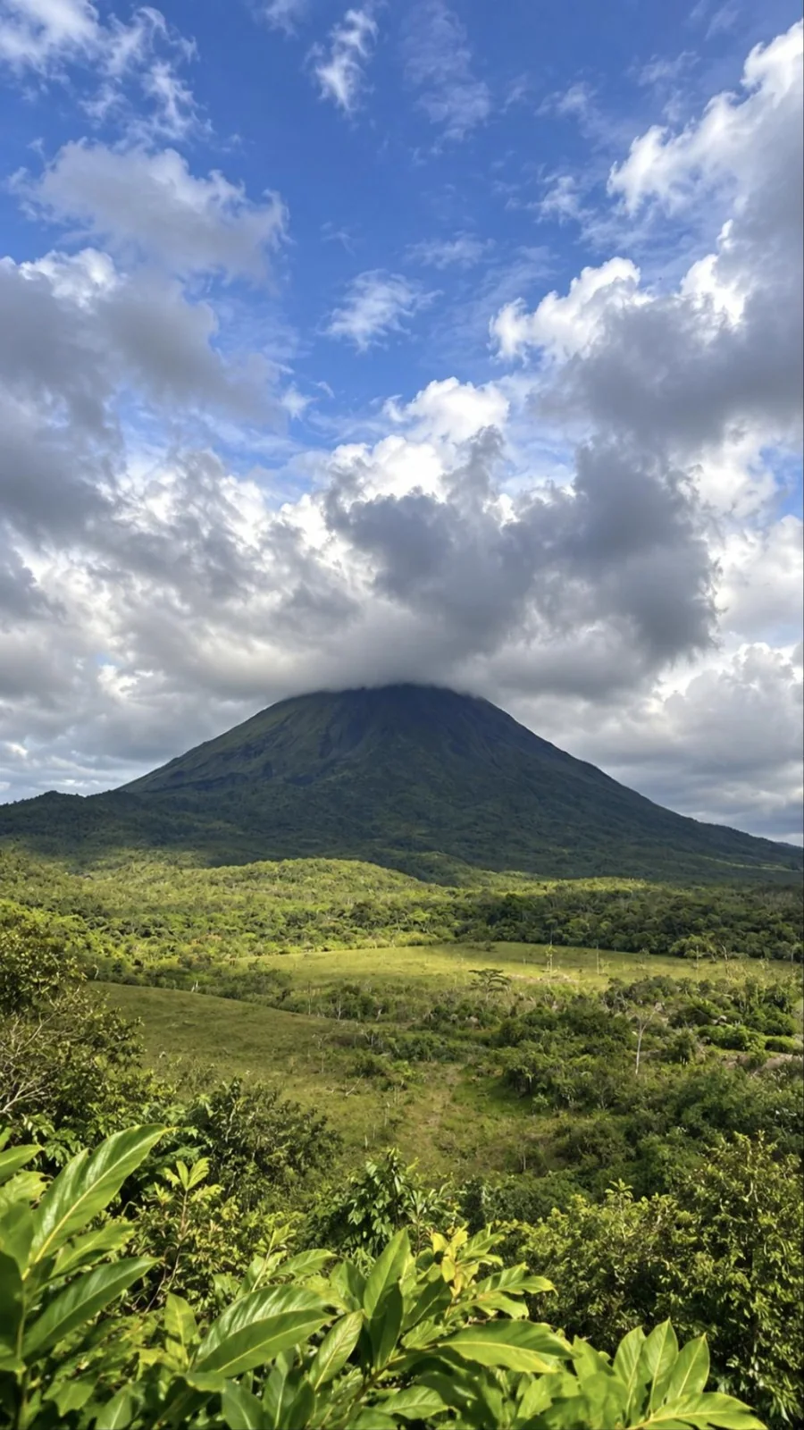 Arenal Volcano partly wrapped in clouds above the rainforest