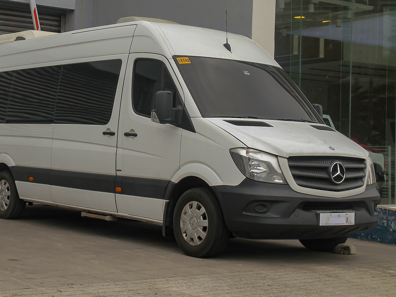 White Mercedes-Benz Sprinter passenger van parked outside a building