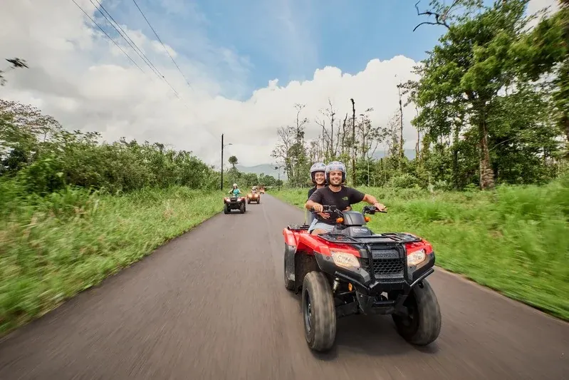 A couple riding a double ATV on the road through the Arenal countryside