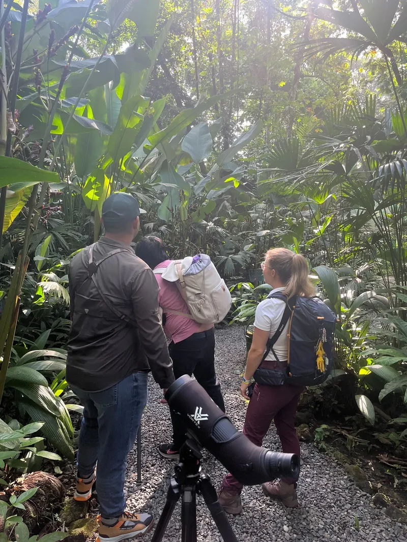 VIVO guide showing a family birds through a spotting scope on a trail at Ecocentro Danaus, La Fortuna