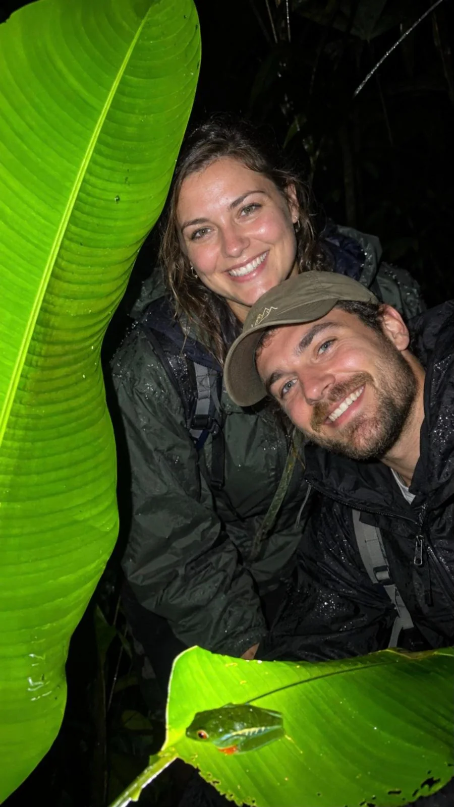 Smiling couple taking a selfie with a red-eyed tree frog on a night tour in La Fortuna, Costa Rica