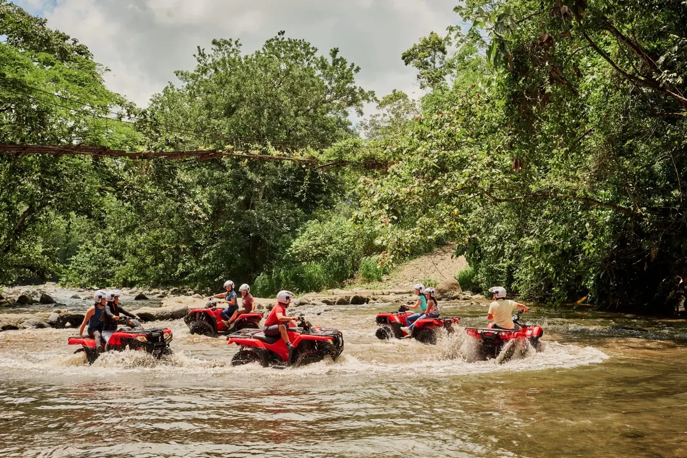 Group of ATV riders in the river surrounded by rainforest