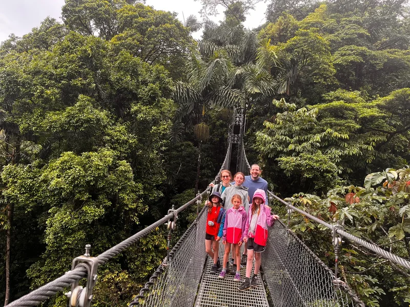 Family with a VIVO guide on a Mistico hanging bridge above the Arenal rainforest canopy
