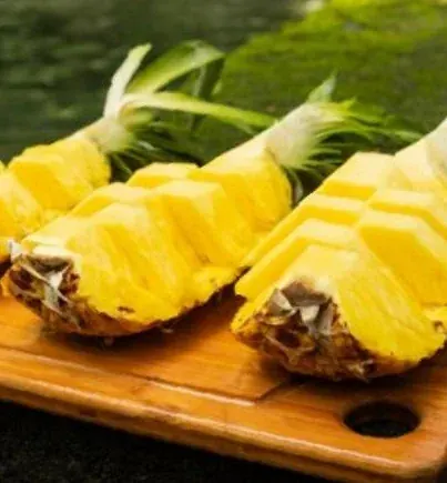 Fresh pineapple served on a wooden board beside the pool