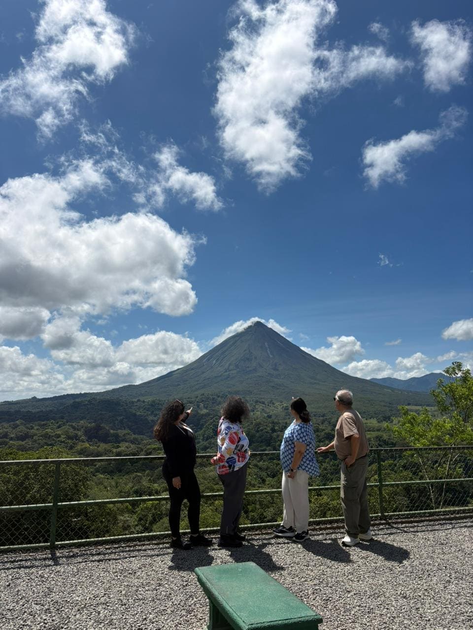 Group of four at an Arenal Volcano viewpoint with the cone behind them