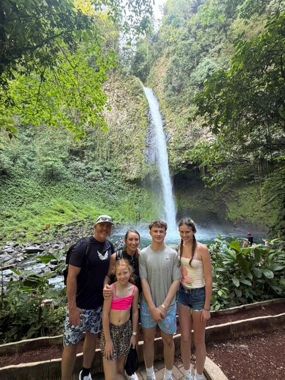 Family group of five posing in front of a Costa Rican jungle waterfall