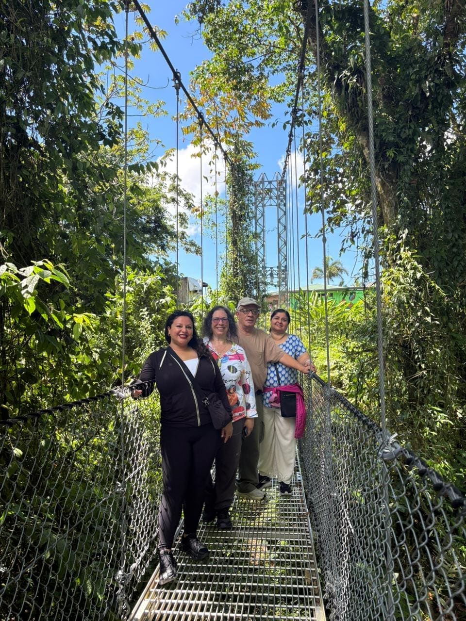 Group of four crossing a hanging bridge above the cloud forest canopy